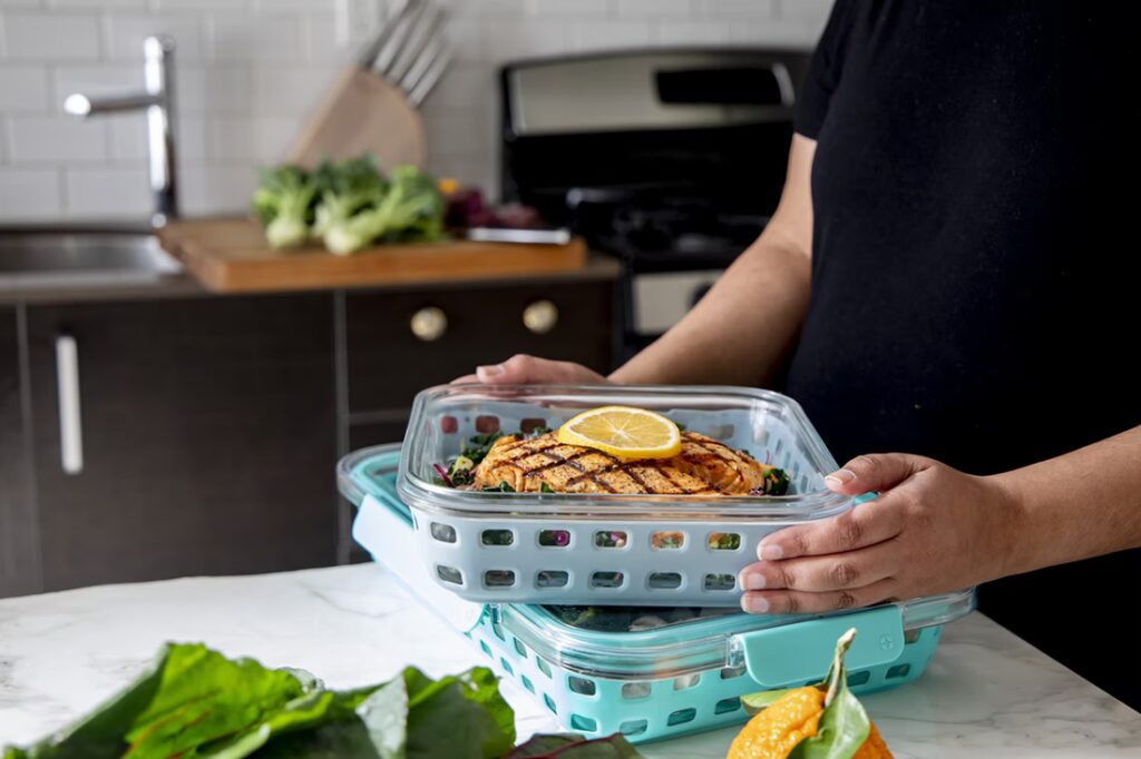 Woman meal prepping grilled chicken over a bed of leafy greens