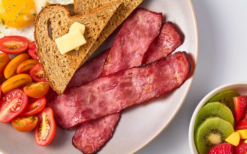 Plated healthy breakfast including toast, turkey bacon and a side of fruit.