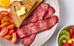 Plated healthy breakfast including toast, turkey bacon and a side of fruit.