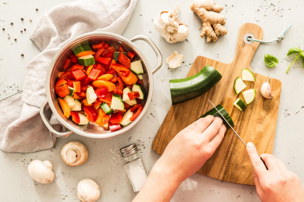 Woman preparing ingredients for a one pot meal of veggies on a kitchen counter