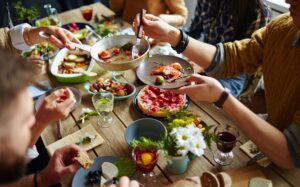 Group of people (hands shown) sitting around a table with food